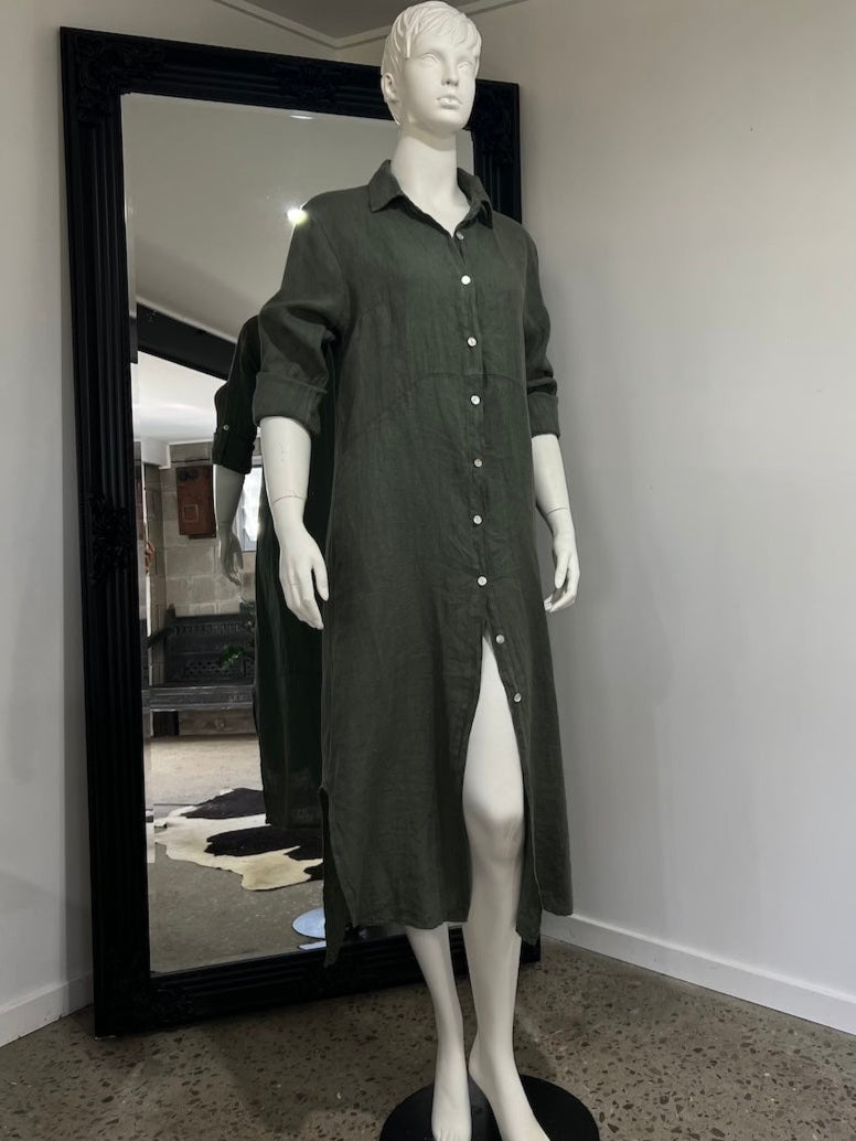 Mannequin wearing a dark green dress in front of a large mirror in a room.